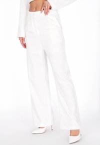 Pantaloni albi cu croi larg, talie înaltă, cu fermoar frontal și închidere cu nasture, textură netedă și buzunare laterale.