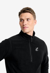 Schwarzer Fleece-Pullover mit Reißverschlusskragen, der eine glatte Textur aufweist und ein gesticktes Logo auf der linken Brust hat.