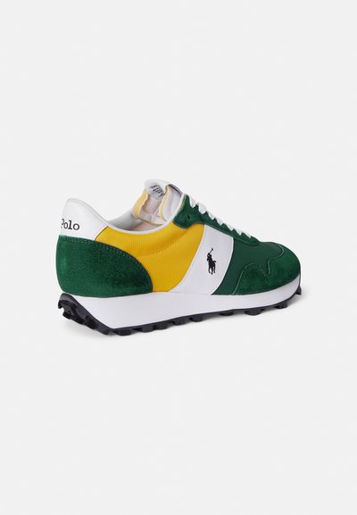 Πράσινο και κίτρινο αθλητικό παπούτσι με επάνω μέρος από σουέντ και ύφασμα, λευκές λεπτομέρειες, υφασμένο πέλμα και μαύρη λαστιχένια σόλα. Λογότυπο στο πλάι.