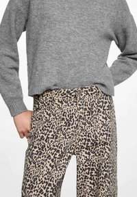 Hlače s uzorkom leopard u bež i crnoj boji, izrađene od laganog materijala. Imaju prednje džepove i klasično kopčanje na dugme.