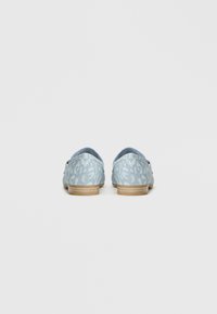 Φωτεινά μπλε τζιν παπούτσια με υφασμάτινη υφή στο άνω μέρος, στρογγυλή πλάτη και φυσική ξύλινη σόλα. Απλός σχεδιασμός χωρίς πρόσθετα εξαρτήματα.