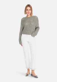Grauer Strickpullover mit langen Ärmeln, kombiniert mit weißen, geraden Jeans und silbernen, spitz zulaufenden Ballerinas, die ein strukturiertes Design aufweisen.