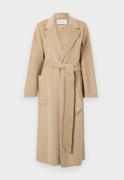 Pitkä beige villakangas takki, jossa on leveät kaulukset, kaksi etutaskua ja matching vyö solmittuna vyötärölle.