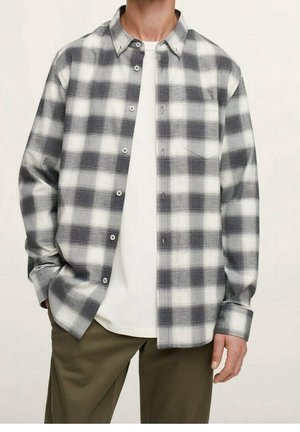 Grå og hvide ternede flannel-skjorte med knaplukning, enkelt brystlomme og lange ærmer, lagdelt over en hvid t-shirt.