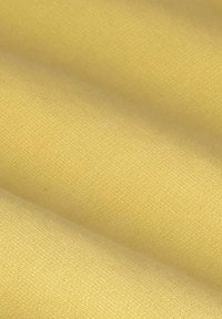 Tissu jaune clair lisse avec une texture fine et de doux plis créant des ombres délicates sur la surface.