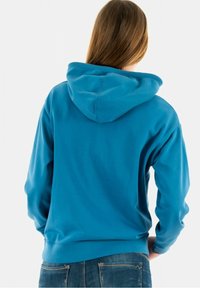 Blå bomulls-hoodie med dragsko på luvan, långa ärmar och en avslappnad passform. Baksidan har en slät yta och en kenguruficka.