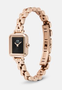 Rózsaarany színű rozsdamentes acél karóra téglalap alakú fekete számlappal, arany mutatókkal, összekapcsolt karkötő szíjjal, a Daniel Wellington logó a számlapon.