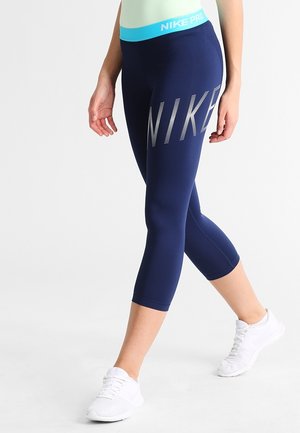 Leggings capri bleu marine en matière lisse et extensible. Dotés d'un audacieux logo argenté « NIKE » et d'une taille turquoise.