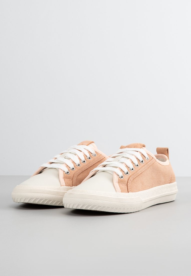 Zapatillas de ante rosa claro con puntera y suela de goma blanca, que presentan cordones blancos y ojales metálicos. Diseño minimalista con pestaña en el talón trasero.