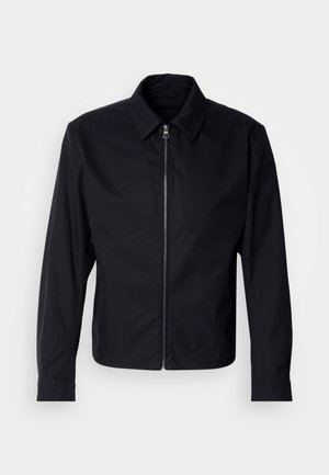 Črna zip-up jakna z ovratnikom, ki se spusti dol, in dolgimi rokavi. Narejena iz gladkega blaga, z minimalističnim dizajnom in brez vidnih vzorcev.