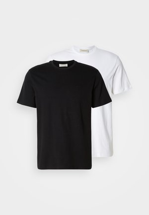 Zwei schlichte Baumwoll-T-Shirts, eines schwarz vor einem weißen platziert, beide mit kurzen Ärmeln und runden Halsausschnitten.