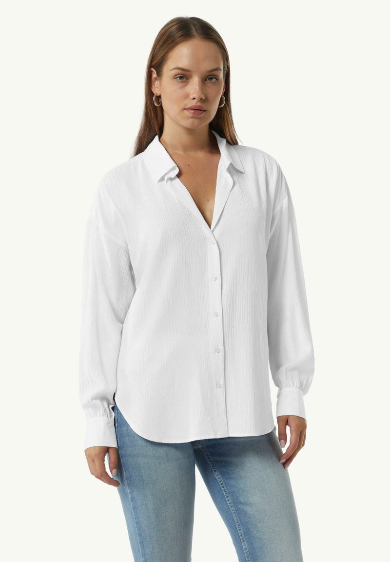 Wit button-up shirt met lange mouwen, van textuurstof, klassieke kraag en afgeronde zoom; gedragen over lichtblauwe jeans.