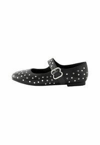 Chaussure Mary Jane en cuir noir avec des clous argentés, bout rond et une sangle à boucle sur le côté. Semelle plate avec une finition texturée.