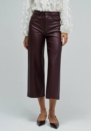 Pantalons courts en simili cuir bordeaux à taille haute, avec un détail de bouton et une coupe à jambes larges. Texture lisse et finition soignée.
