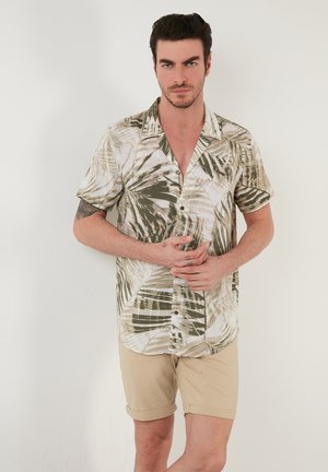 Camisa de manga corta y botonadura hecha de una tela ligera, con un estampado de hojas tropicales en verde y beige, de corte relajado.
