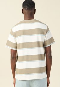 Korte mouwen, ronde hals shirt met horizontale strepen in beige, wit en lichtblauw. De stof heeft een gestructureerde afwerking en een ontspannen pasvorm.