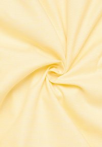Tessuto giallo texturizzato con un delicato motivo a griglia, che presenta una trama liscia e una finitura morbida, disposto in una formazione a spirale.