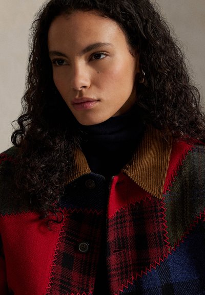 Chaqueta de patchwork en rojo y azul con cuello de pana, que presenta texturas contrastantes y detalles de costuras visibles. Botones en la parte delantera.