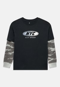 Tricou negru cu logo NYC argintiu. Mâneci lungi cu model camuflaj și manșete striate în gri deschis. Croială lejeră, material din bumbac.