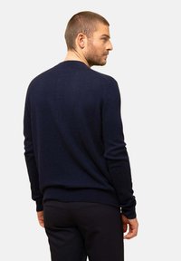 Suéter azul marino hecho de tela suave, con cuello redondo, mangas largas y puños y dobladillo acanalados, mostrado desde la parte de atrás.