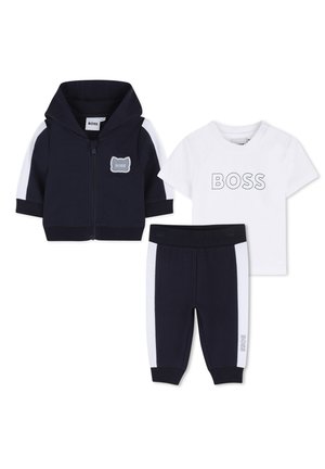 Ensemble trois pièces bleu marine comprenant un sweat à capuche zippé avec des accents blancs, un t-shirt blanc à manches courtes avec le texte « BOSS », et un pantalon assorti.
