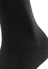 Zwarte sokken gemaakt van glad, rekbaar materiaal. Voorzien van een verstevigde hiel en teen. Licht geribbelde textuur langs de boord.