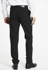 Zwarte pantalons met een tailor-fit, voorzien van twee achterzakken met knopen en een gladde textuur, gecombineerd met zwarte dresschoenen.