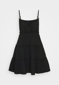 Vestido negro de tirantes finos y con volantes, con un detalle de lazada en el escote y una tela texturizada. Silueta fluida.