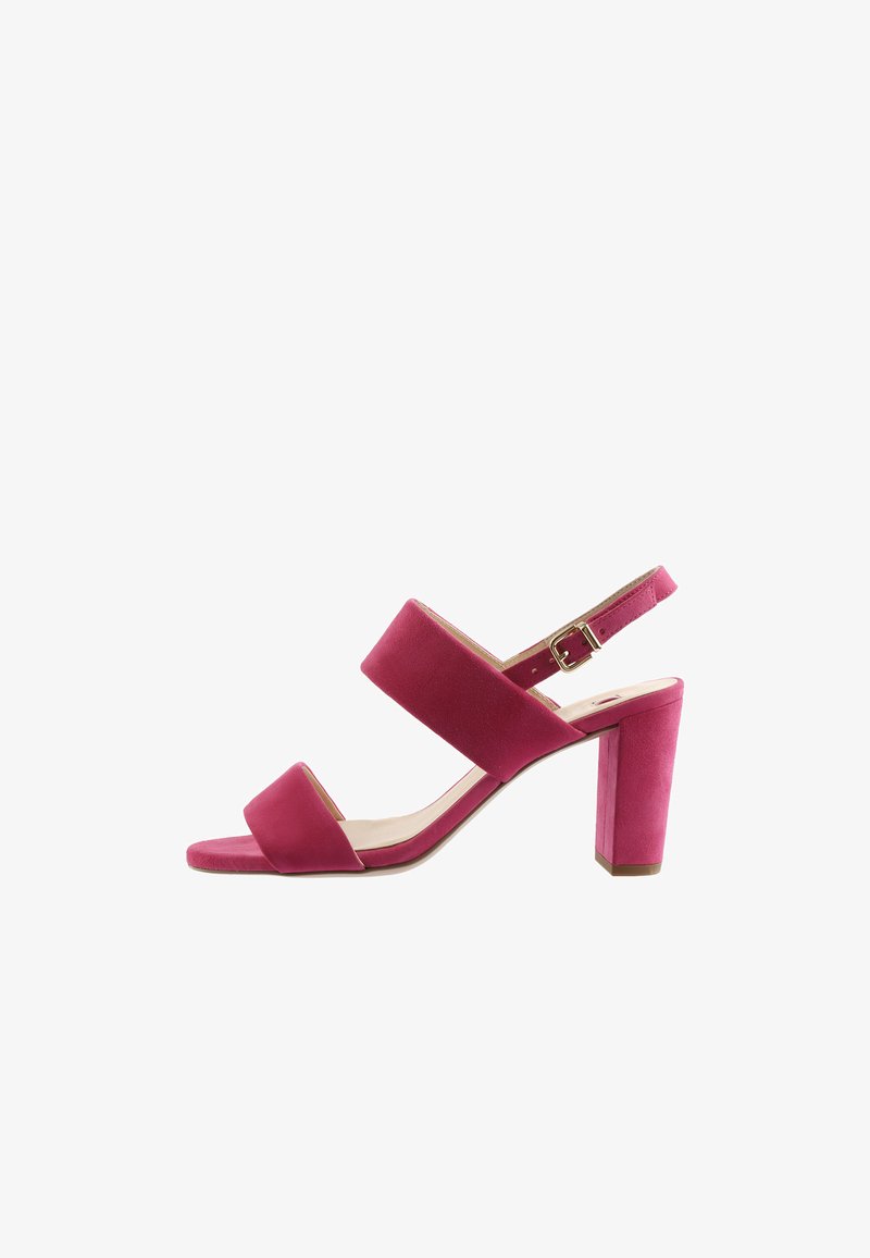 Roze suède damessandaal met hoge hak, voorzien van twee brede banden en een verstelbare enkelband met gesp, afgebeeld tegen een witte achtergrond.