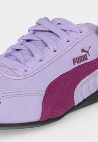 Κοντινό πλάνο ενός παπουτσιού Puma σε λεβάντα με μοβ λεπτομέρειες, κορδόνια και λογότυπο στο πλάι, με μαύρη σόλα.