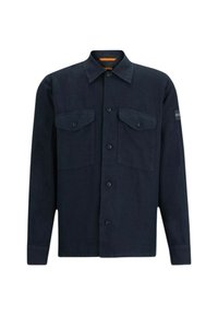 Camisa de color azul oscuro en una tela ligera, con dos bolsillos en el pecho, cierre de botones en la parte delantera y un cuello clásico. Branding notable en la manga.