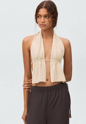 Beige haltertop met een strik aan de voorkant, van lichtgewicht stof en met een gedrapeerd ontwerp. Gecombineerd met losse brown pants met een elastische tailleband.