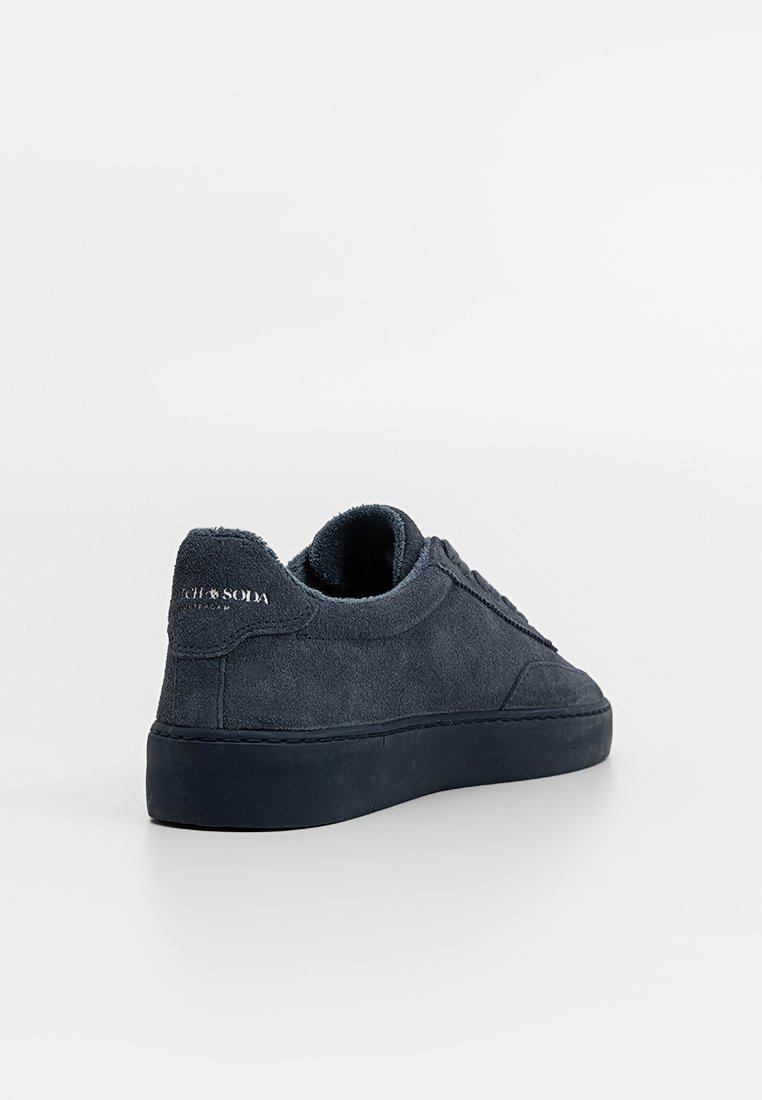 Marineblauwe suède sneaker met een gestructureerde oppervlakte, gevoerde kraag en logo-detail op de hiel. Voorzien van een dikke rubberen zool en een glad interieur.