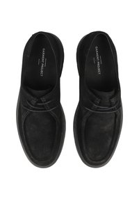 Sorte ruskinds slip-on sko med en rund tå, tynde snørebånd og en struktureret sort gummisål. Logo trykt på indersålen.