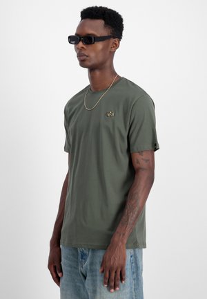 Olive green short-sleeve t-shirt in a cotton blend, featuring a small embroidered logo on the chest and a relaxed fit, paired with light jeans.