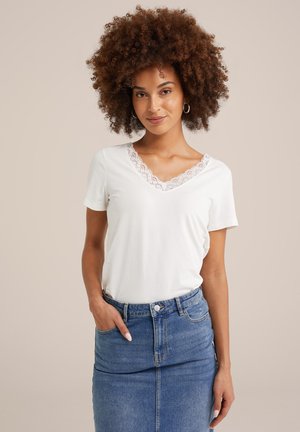 T-shirt blanc à manches courtes avec décolleté en V et dentelle, associé à une jupe en denim avec boutons sur le devant et poches.