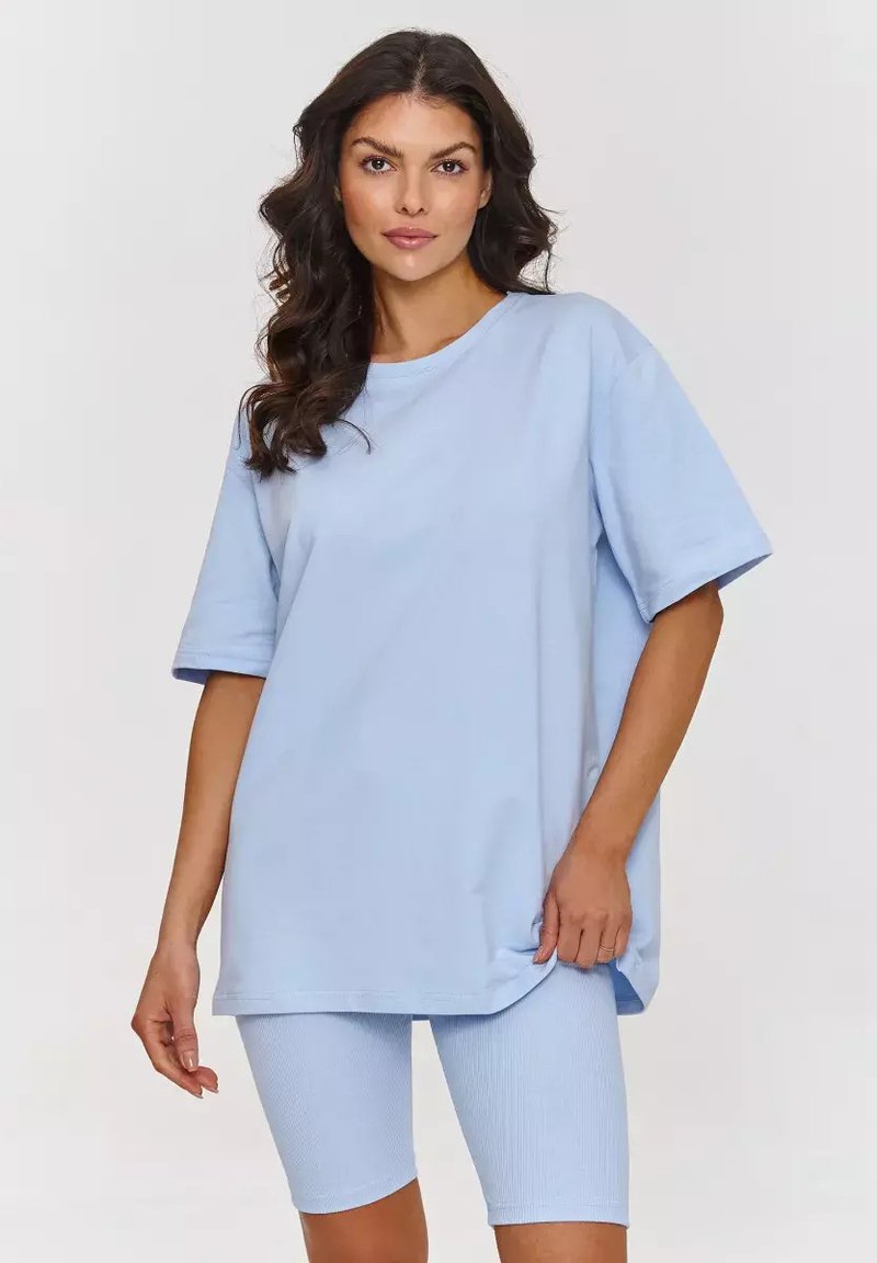 Jasnoniebieski oversize'owy t-shirt z krótkimi rękawami, wykonany z miękkiej bawełny, zestawiony z dopasowanymi rybaczkami o prążkowanej strukturze, zaprojektowany z myślą o komforcie.
