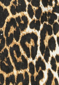 Tela con estampado de leopardo que presenta grandes manchas negras y marrón dorado sobre un fondo blanco, con una apariencia texturizada y tejida.