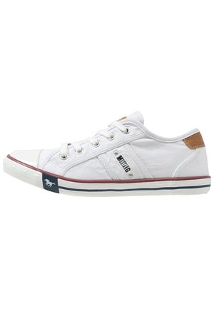 White canvas sneaker with a rubber toe cap, brown leather accent on the heel, and a navy stripe on the sole. Features prominent eyelets and branding.