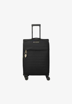 Maleta rígida negra con estrías horizontales, asa telescópica, bolsillo frontal con cremallera, cuatro ruedas y un charm dorado de flor en el tirador de la cremallera.