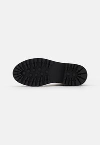 Black rubber shoe sole featuring a tread pattern with hexagonal and linear grooves for traction. Markings indicate shoe size 37.