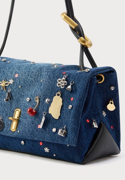 Borsa in denim con rifiniture in pelle nera, decorata con vari ciondoli, strass ed elementi decorativi in argento, oro e rosso.