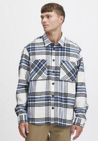 Karierte Flanellbluse in Weiß mit blauen und schwarzen Linien, mit Knopfleiste, zwei Brusttaschen und langen Ärmeln.