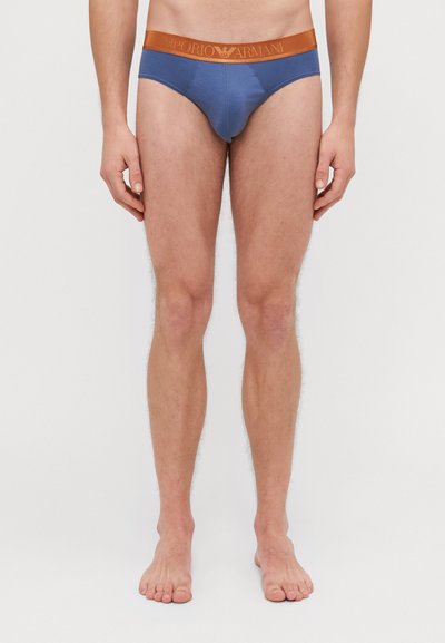 Chiloți din bumbac albastru cu un elastic portocalie pe care se află logo-ul Emporio Armani. Designul este ajustat, cu o textură netedă și cusături minime.