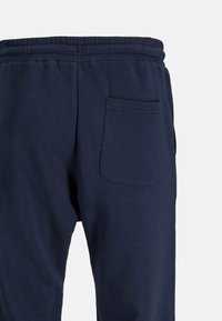 Navy blue sweatpants with a textured cotton blend, elastic waistband, and a single back pocket on the right side.