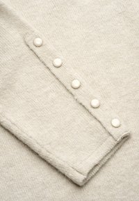 Lichtbeige gebreide sweatermouw met vijf witte knopen langs de manchetten, die een zachte textuur en een gladde afwerking onthult.