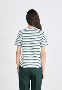 Stripete t-skjorte i hvit med grønne og marineblå striper, korte ermer, rund hals, kombinert med mørkegrønne bukser, glattt bomullstoff.