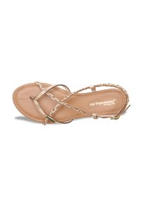 Sandal flat con suola in pelle marrone e scarpe intrecciate in tono oro. Presenta una sottile cinghia alla caviglia e il logo del marchio sulla soletta.