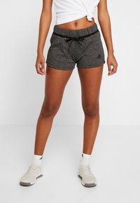 Pantalones cortos deportivos grises con una cintura ajustable de cordón, diseño elegante y bolsillos laterales, combinados con zapatillas deportivas blancas y calcetines.