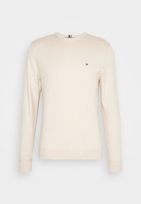 Beige trui met lange mouwen gemaakt van zachte stof. Voorzien van een ronde hals en een klein logo-opdruk op de linkerborst. Ribgebreide manchetten en onderzijde.